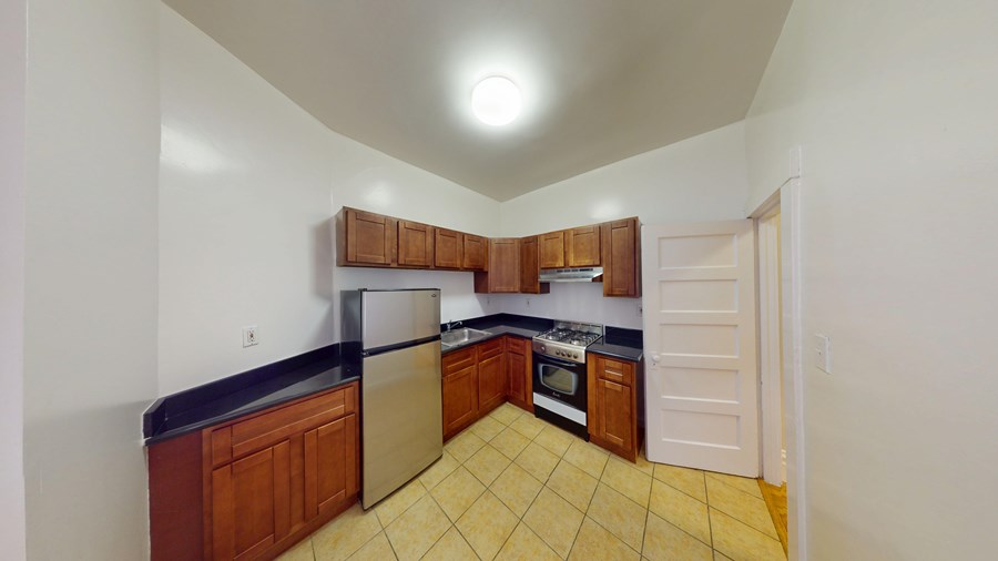 A kitchen with wooden cabinets and a tile floor.